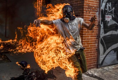 A demonstrator catches fire after the gas tank of a police motorbike exploded during clashes in a protest against Venezuelan President Nicolas Maduro, in Caracas on May 3, 2017.Venezuela's angry opposition rallied Wednesday vowing huge street protests against President Nicolas Maduro's plan to rewrite the constitution and accusing him of dodging elections to cling to power despite deadly unrest. / AFP PHOTO / JUAN BARRETO