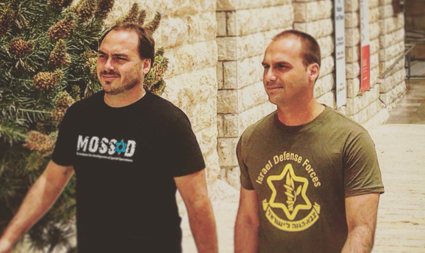 Imagem mostra Flávio e Eduardo Bolsonaro ostentando camisetas de apoio ao serviço de inteligência e das Forças de Defesa de Israel